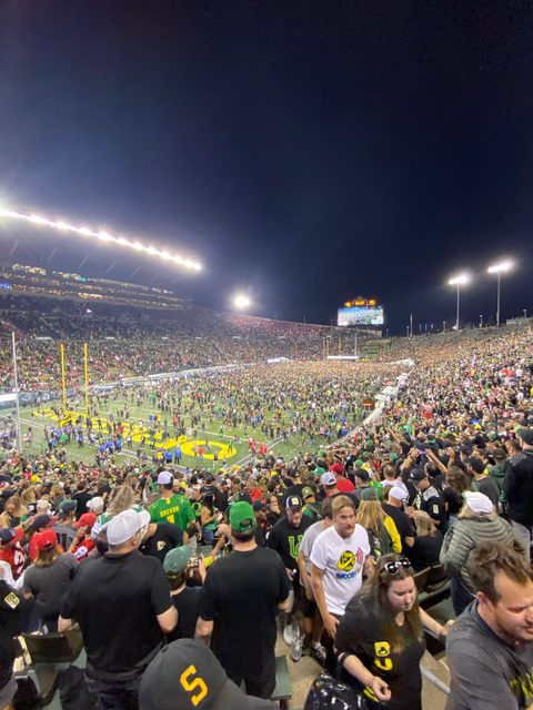 Fans rushing the field at Autzen Stadium at night after a win