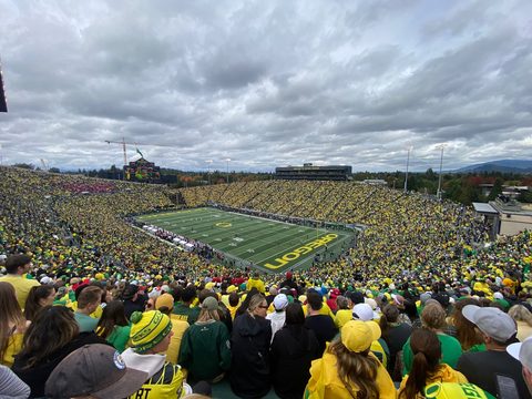 Autzen Stadium from the upper stands, a sea of yellow and green under a cloudy sky