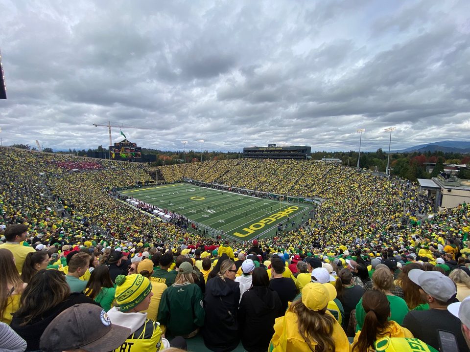 Autzen Stadium from the upper stands, a sea of yellow and green under a cloudy sky
