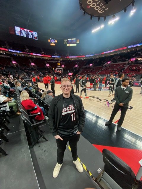 Hayden Schuster courtside at the Moda Center in a Rip City jersey before a Trail Blazers game